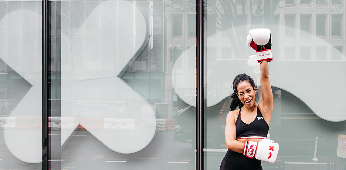 Person posing with boxing gloves outside of a Rumble building